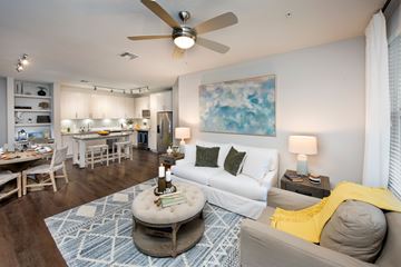 Maitland apartment for rent - A living room with a white couch, a round ottoman, and a painting on the wall.