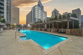 Charlotte apartment for rent - A swimming pool with seating around it and tall buildings in the background.