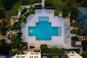 Tampa apartment for rent - A large pool surrounded by palm trees and a white building.