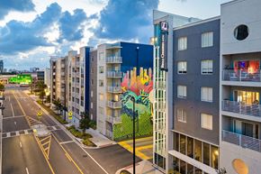 Tampa apartment for rent - A street view of a city with apartment buildings and a mural on the side of one of the buildings.