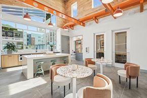 Garner apartment for rent - a communal area with tables and chairs and a kitchen with large windows