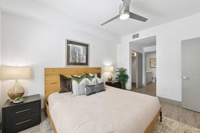 Boca Raton apartment for rent - A bedroom with a large bed, a ceiling fan, and a nightstand with a lamp.