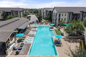 Austin apartment for rent - A large swimming pool surrounded by lounge chairs and umbrellas.