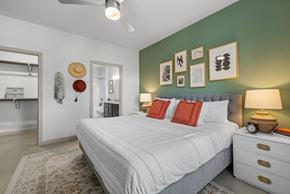 Austin apartment for rent - A bedroom with a white bed, a hat hanging on the wall, and a ceiling fan.