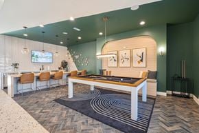 Knightdale townhouse for rent - A billiard table is in the middle of a room, with a bard and TV behind.