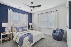 Knightdale townhouse for rent - A bedroom with a bed, chair, and ceiling fan.