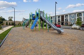 China Grove apartment for rent - A playground with a blue and green slide in the foreground and apartment buildings in the background.