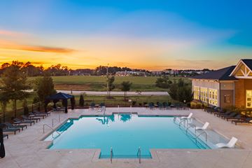 Holly Springs apartment for rent - A large outdoor swimming pool surrounded by lounge chairs and umbrellas.