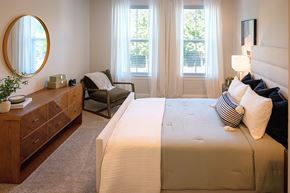 Raleigh apartment for rent - A bedroom with a large bed and a chair by the window.