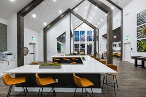 Duluth apartment for rent - A white table with orange chairs is in the foreground of a modern room.