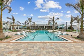 Vero Beach apartment for rent - A large swimming pool surrounded by palm trees and lounge chairs.
