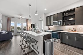 Winter Park apartment for rent - A modern kitchen with a white island and black bar stools.