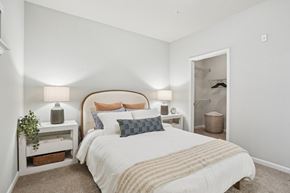 Mooresville apartment for rent - A bedroom with a large bed and a nightstand with a lamp.