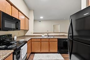 Mansfield apartment for rent - A kitchen with a black refrigerator and wooden cabinets.