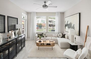 Raleigh apartment for rent - A modern living room with a white sofa, a wooden coffee table, and a large painting on the wall.