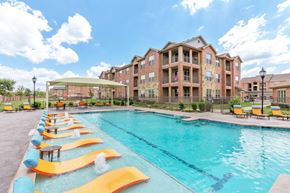 Garland apartment for rent - The Parc at Garland pool with yellow sun bathing lounge chairs.
