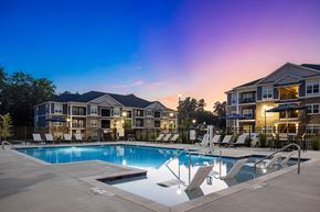 Wake Forest apartment for rent - A swimming pool surrounded by lounge chairs in front of apartment buildings.