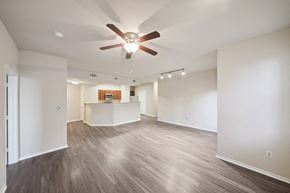 Denton apartment for rent - an empty living room with a ceiling fan and a kitchen