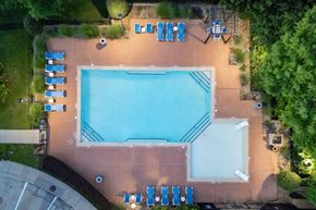 Denton apartment for rent - An aerial view of a swimming pool surrounded by lounge chairs and trees.