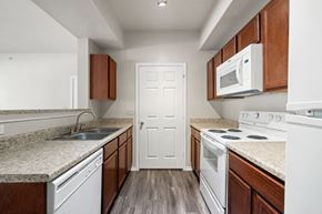 Denton apartment for rent - A kitchen with white appliances and wooden cabinets.