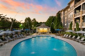 Johns Creek apartment for rent - A large swimming pool surrounded by lounge chairs and umbrellas.