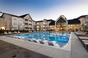 Duluth apartment for rent - A large swimming pool in front of a building with lounge chairs around it.