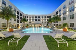 Jacksonville apartment for rent - A large white building with a pool in the middle of a grassy area.