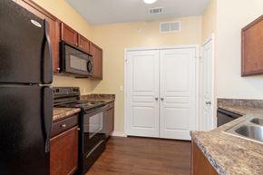 Rockwall apartment for rent - Apartment kitchen showing appliances and laundry area doors.