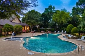 Rockwall apartment for rent - A swimming pool surrounded by trees and a house.
