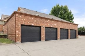Rockwall apartment for rent - A red brick building with three black garage doors.