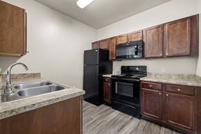 Rockwall apartment for rent - A kitchen with black appliances and wooden cabinets.
