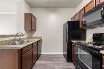 Rockwall apartment for rent - A kitchen with a black refrigerator and stove top oven.