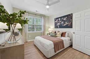 Ashburn apartment for rent - A bedroom with a bed, window, ceiling fan, dresser and a painting on the wall.