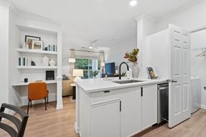Ashburn apartment for rent - A kitchen with white cabinets, farmhouse sink, built in bookshelves, desk area and a wooden floor.