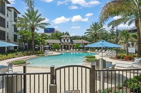 Orlando apartment for rent - A pool surrounded by palm trees and a fence.