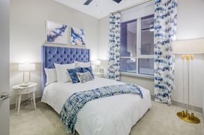 Raleigh apartment for rent - a bedroom with a bed and a window with blue and white curtains