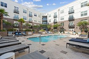 Charleston apartment for rent - a swimming pool with lounge chairs in front of an apartment building