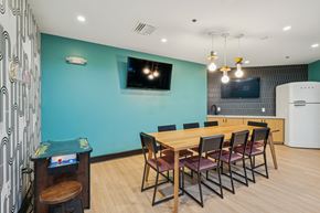 Raleigh apartment for rent - a dining room with a wooden table and chairs and a blue wall with a television