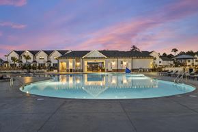 Wilmington apartment for rent - A large swimming pool in front of a building with lights on.