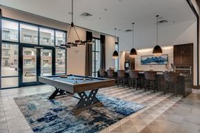 Dallas apartment for rent - A pool table is in the middle of a room with a view of apartment buildings outside.