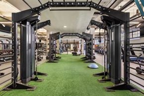 Durham apartment for rent - a green carpeted gym floor with a row of exercise equipment on the left and a row