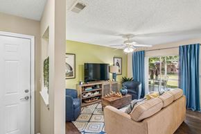 Rockledge apartment for rent - A living room with a couch, a television, and a fan.