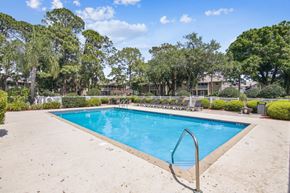 Rockledge apartment for rent - A swimming pool surrounded by trees and bushes.