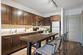Frisco apartment for rent - A kitchen with brown cabinets and a table with chairs.