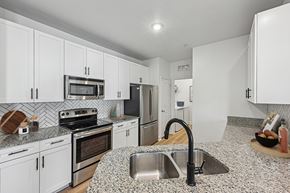 Orlando apartment for rent - A kitchen with white cabinets and a granite countertop.
