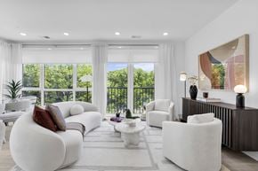 Englewood Cliffs apartment for rent - A modern living room with white furniture and a view of trees outside the window.