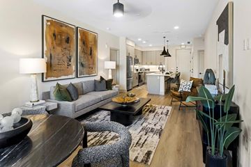 Phoenix apartment for rent - A modern living room with a grey sofa, a wooden table, and a large abstract painting on the wall.