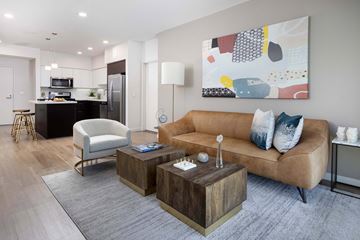 Irvine apartment for rent - A modern living room with a brown sofa, a wooden coffee table, and a large abstract painting on the wall.