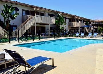 San Diego apartment for rent - A pool area with sun loungers and a building in the background.