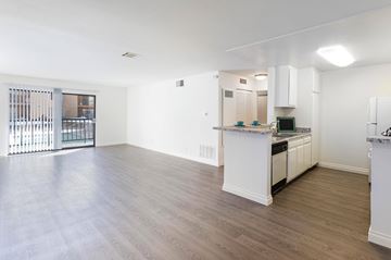 Northridge apartment for rent - A spacious kitchen and living room with white cabinets and a wooden floor.